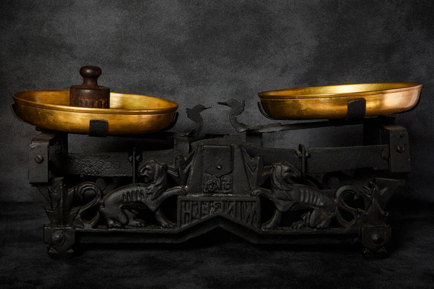 escalas antiquárias com duas taças douradas e pequeno peso
 - Foto, Imagem