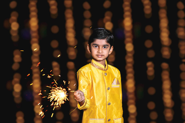 Cute Indian child celebrating Diwali festival with cracker and sparkle - Zdjęcie, obraz