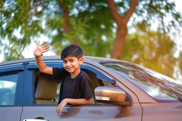 Cute Indian Child waving from car window - Foto, afbeelding