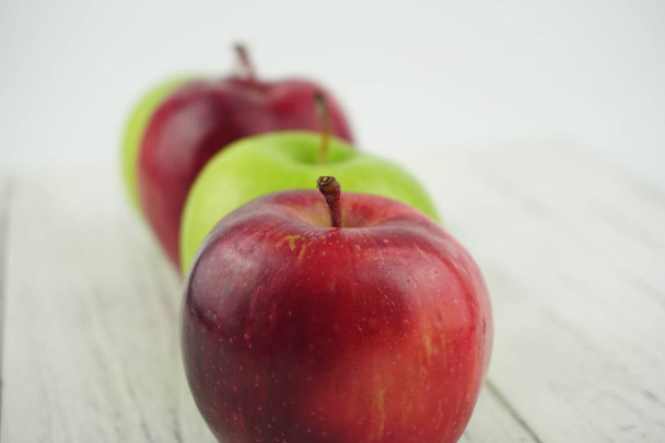 Czerwone i zielone jabłka na drewnianej strukturze tła. Zdrowa żywność  - Zdjęcie, obraz