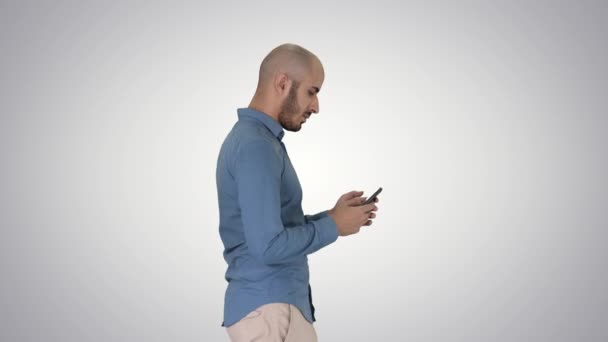 Young man walking and using a phone on gradient background. - Filmmaterial, Video