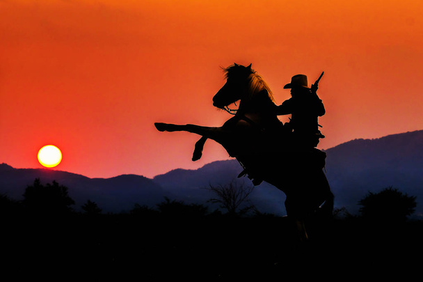 Cowboy siluetti hevosen aikana mukava auringonlasku
 - Valokuva, kuva