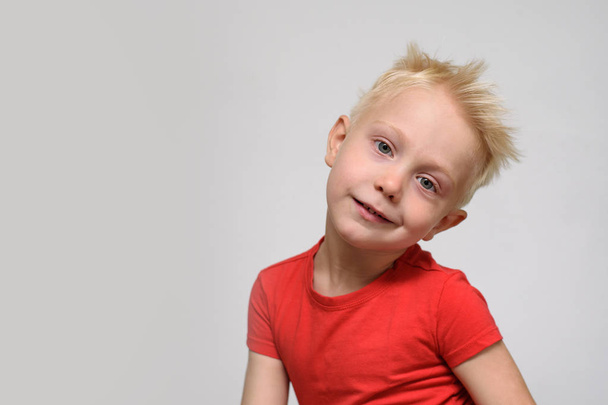 Petit garçon blond souriant en t-shirt rouge. Portrait. Espace pour le texte. Fond blanc
 - Photo, image
