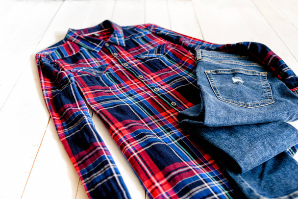 Clothes concept. Checkered shirt and jeans on wooden background. Side view - Photo, Image