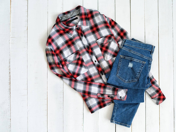 Red and white checkered shirt and jeans on a wooden background. Top view - Photo, Image