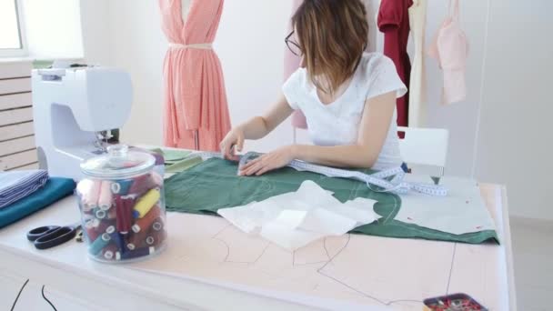 Hobby en kleine bedrijven. Jonge vrouwelijke kleermaker werken met doek stof in workshop - Video