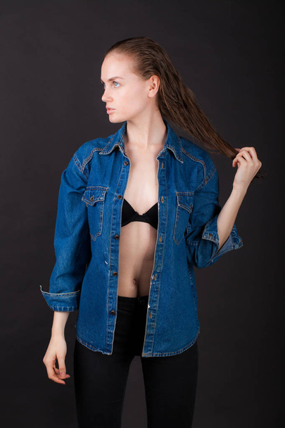 studio portrait of a very thin young woman in lingerie with wet hair and jeans jacket - Photo, Image