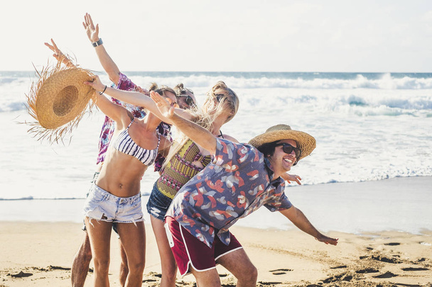 Grupo de amigos divirtiéndose y jugando en la playa cerca del mar durante el día
 - Foto, imagen