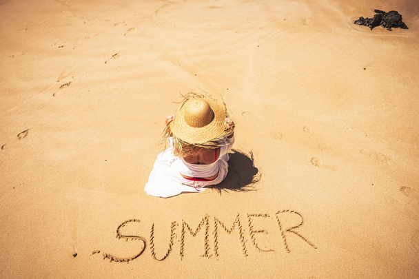 nainen rannalla nauttia auringosta sana kesä kirjoitti hiekkaan
  - Valokuva, kuva