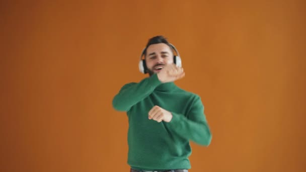 Attractive millennial listening to music through headphones dancing having fun - Video, Çekim