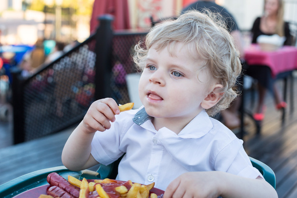 schattige kleine jongen Franse frietjes eten in de zomer - Foto, afbeelding