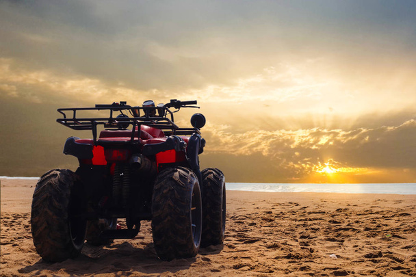 négy Wheeler Dirt Bike homokja tenger strand naplementekor - Fotó, kép