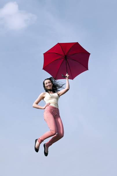 Mulher pulando com guarda-chuva no céu azul
 - Foto, Imagem