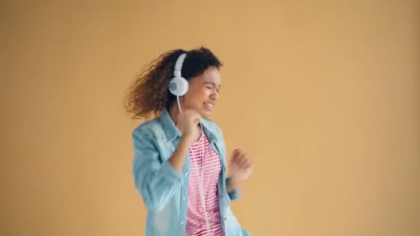 Portrait of playful girl in headphones listening to music dancing and singing - Video