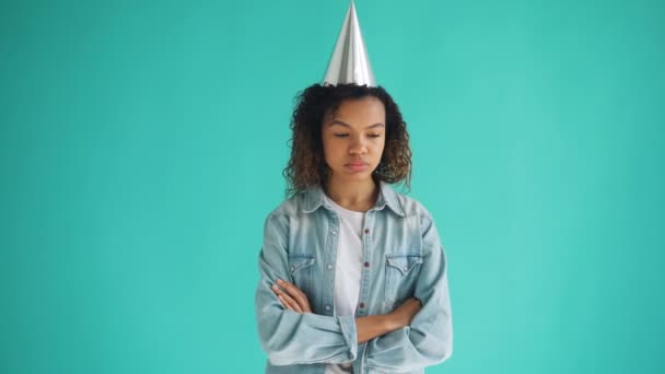 Portrait of unhappy mixed race girl in party hat standing with arms crossed - Filmmaterial, Video