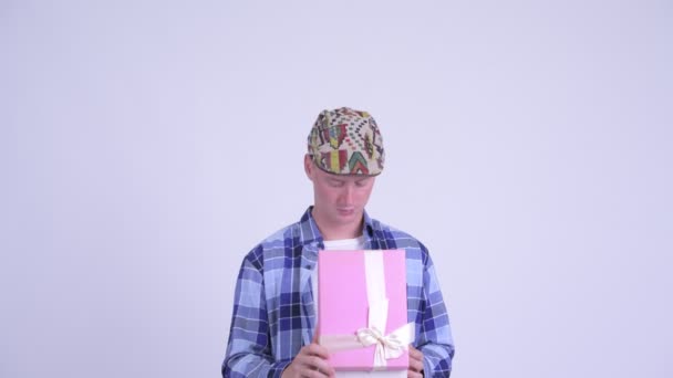 Happy young hipster man opening gift box and looking surprised - Materiaali, video