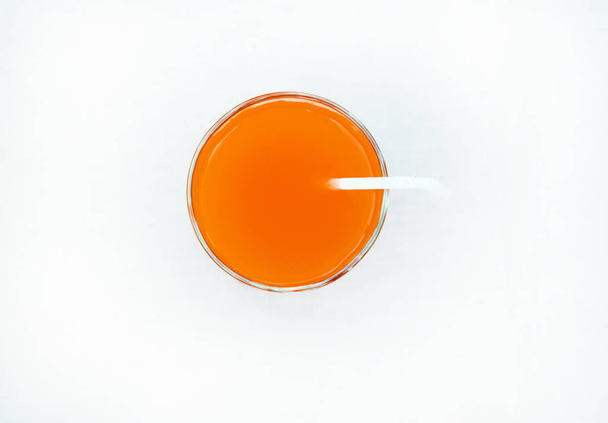 Bebida de verão - suco de toranja recentemente espremido em um copo com um tubo de palha, vista superior, isolado em um fundo branco com recorte, minimalismo
 - Foto, Imagem