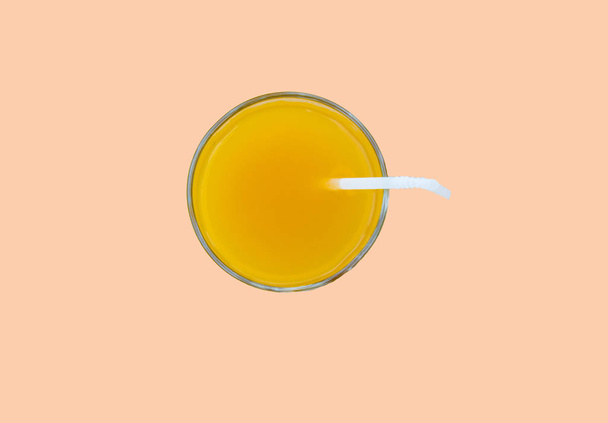 Bebida de verano: jugo de naranja recién exprimido en un vaso con tubo de paja, vista superior, aislado sobre un fondo rosa con recorte, estilo minimalista
 - Foto, Imagen