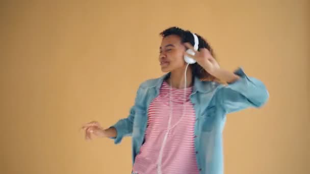 Portrait of cute African American lady listening to music in headphones dancing - Filmati, video