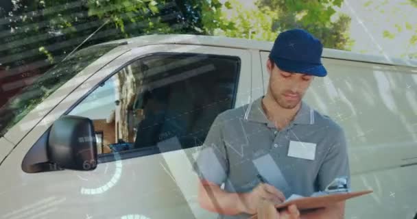 Front view of a deliveryman beside a van writing on a clipboard smiles and signals a thumbs up. Digital animation of graphs and statistics are seen running in the foreground 4k - Video, Çekim