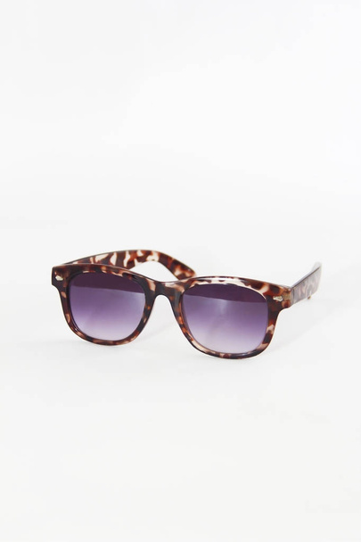 occhiali da sole in una montatura di plastica marrone e lenti viola su uno sfondo bianco
 - Foto, immagini