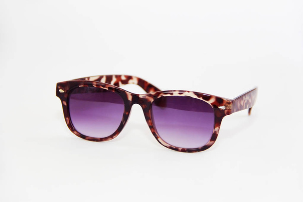 солнцезащитные очки в коричневой пластиковой рамке и фиолетовые линзы на белом фоне
 - Фото, изображение