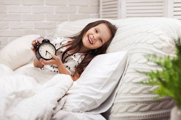 little child girl in pyjamas with clock - Valokuva, kuva