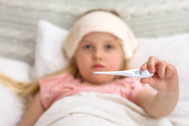Chora mała dziewczynka leżąca w łóżku z termometru. - Zdjęcie, obraz
