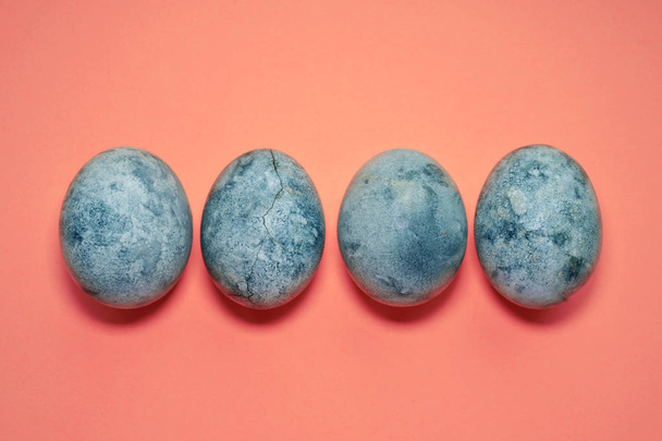 vier blaue Eier, bemalt mit Tee-Hibiskus, auf rosa Hintergrund, ähnlich wie Planet und Marmor mit Kopierraum - Foto, Bild