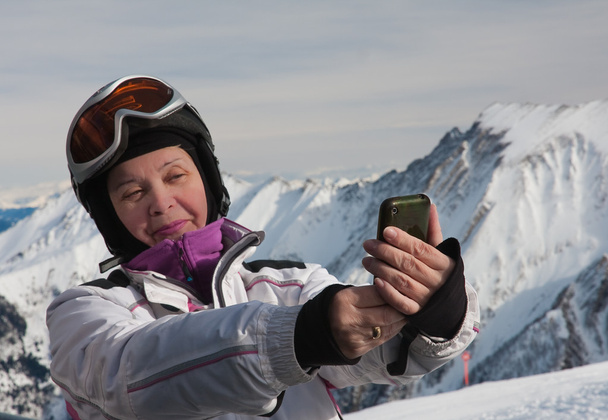 A woman photographs the skier himself smartphone - Foto, afbeelding