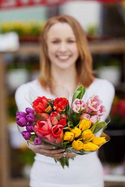 Attractive young woman showing a bunch of flowers - Фото, изображение
