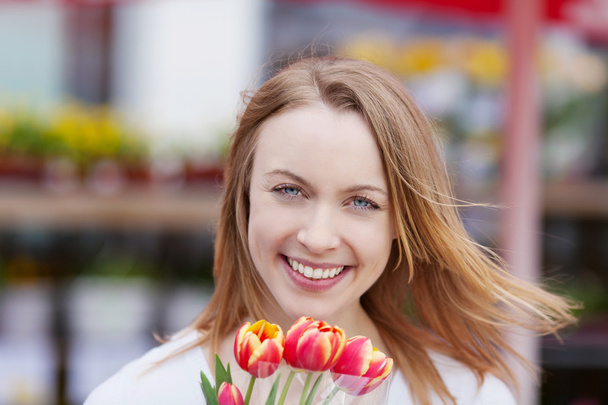 Pretty female smiling while holding fresh tulips - Photo, Image