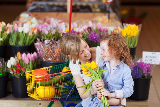 Smiling mother and daughter buying tulips - Photo, Image