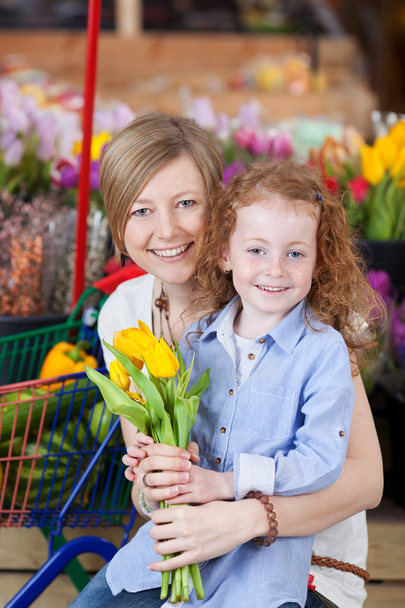 Girl And Mother Holding Flowers In Supermarket - 写真・画像