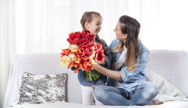 Dia da mãe. Filhinha com flores felicita seu mot
 - Foto, Imagem