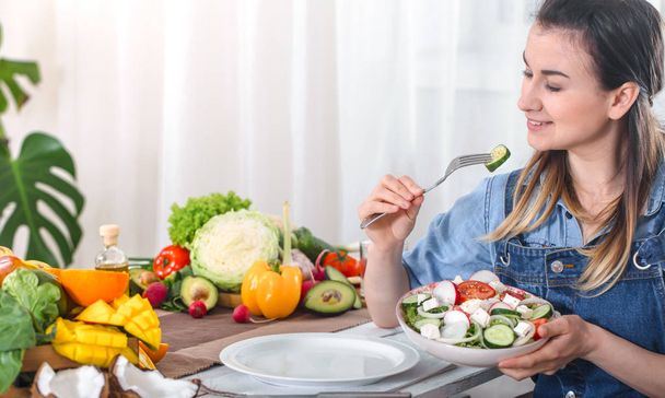 Young and happy woman eating salad at the table - Photo, Image