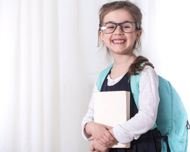 Κορίτσι-δημοτικό σχολείο μαθητής με ένα σακίδιο και ένα βιβλίο - Φωτογραφία, εικόνα