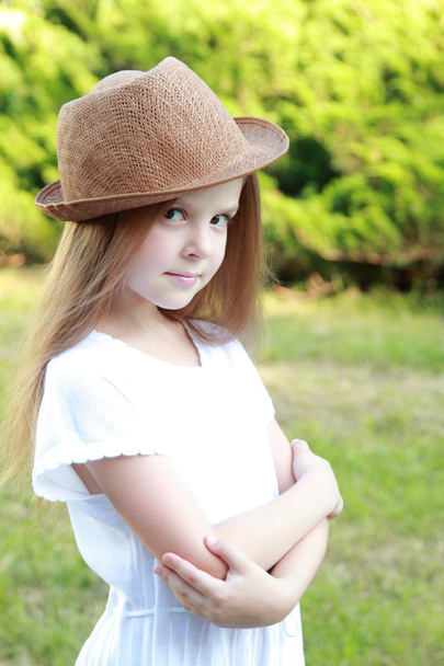 Caucasian smiling girl in a white dress and a hat outdoors - 写真・画像