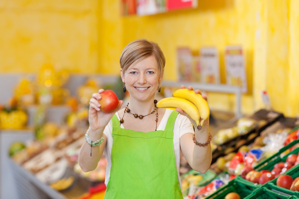 Friendly saleswoman showing different fruits - Foto, Imagem