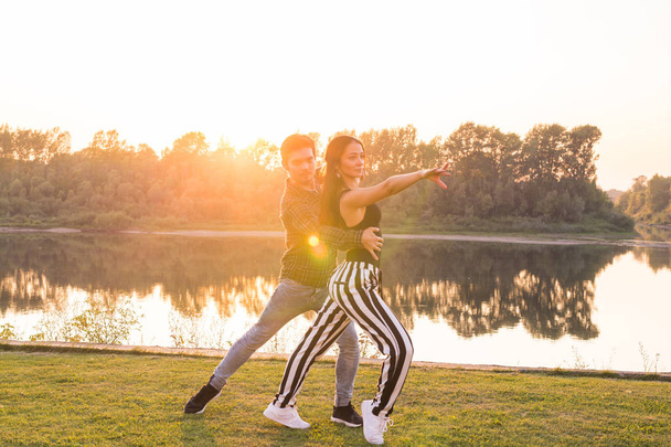Romantic, social dance and people concept - young couple dancing bachata on the background of sunset - Photo, Image