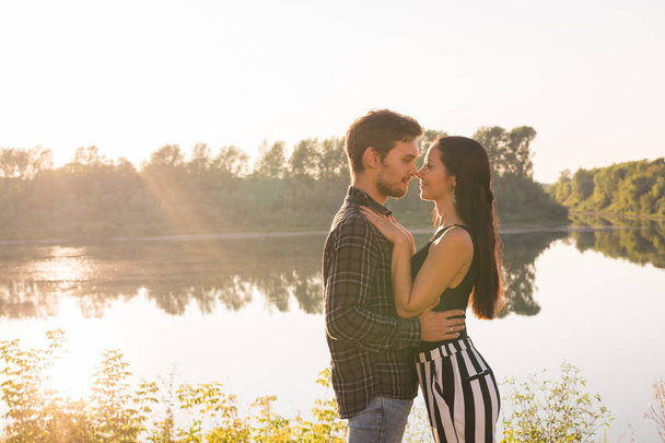 People, love and nature concept - Portrait of young beautiful couple embracing each other while standing over nature background - Photo, image