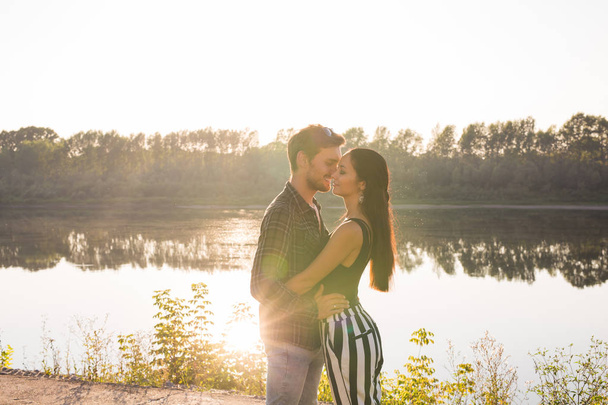 Romántica, naturaleza y concepto de personas - pareja joven besándose en la playa del lago y abrazándose
 - Foto, Imagen