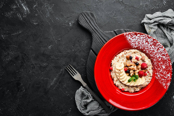 Oatmeal with nuts, banana and wild berries. In the plate. Top view. Flat lay composition Free copy space. - Foto, afbeelding