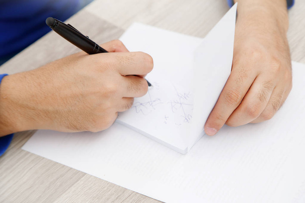 manos de un joven escribiendo en un pedazo de papel
 - Foto, Imagen