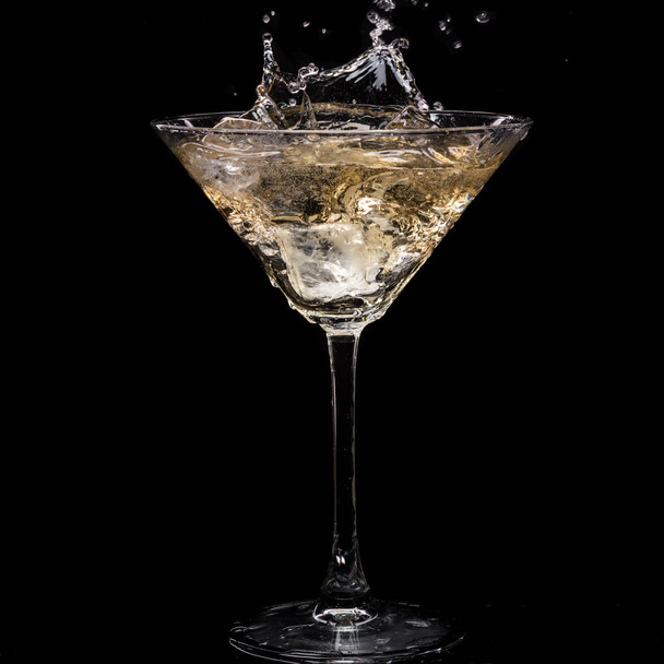 in a martini glass, vermouth ice falls, and splashes with drops on a black background - Foto, immagini
