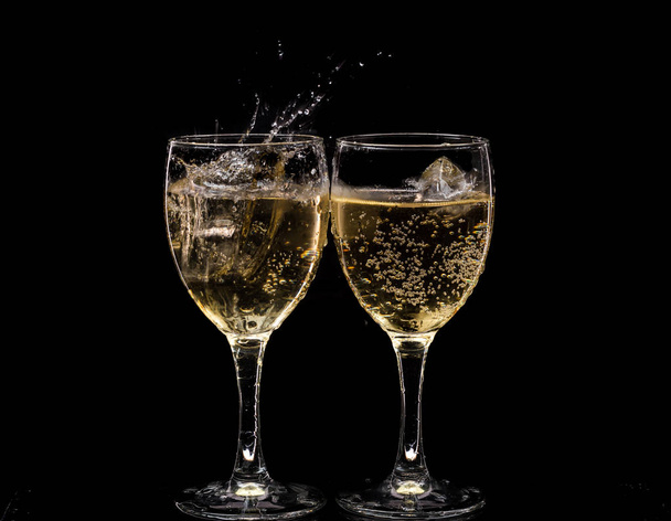 Two crystal wine glasses with a drink, falling ice and splashes - Zdjęcie, obraz