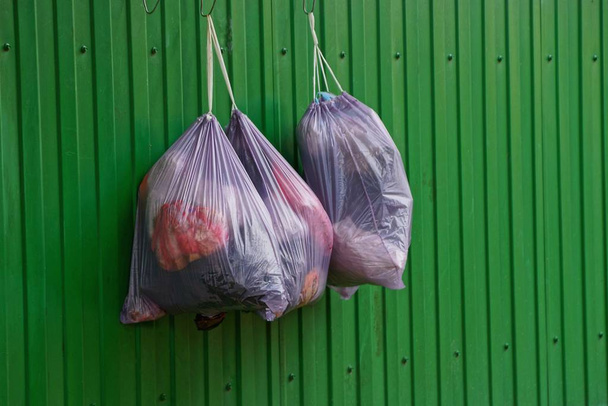 Пакеты с мусором висят на железном заборе на улице
 - Фото, изображение