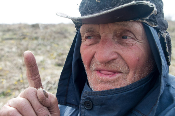 Portrait d'un vieil homme vêtu d'un chapeau et de vêtements salissants qui levait l'index, j'ai une idée
 - Photo, image