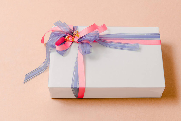 Luksusowe pudełko wiązane z niebieskimi i różowymi wstążkami na różowym tle - Zdjęcie, obraz