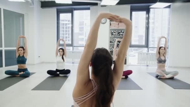 Giovane istruttrice di yoga femminile sta mostrando equilibrio pose e parlando con gli studenti, mentre altre donne stanno ripetendo posture silenziosamente. Concetto di pratica di gruppo
. - Filmati, video